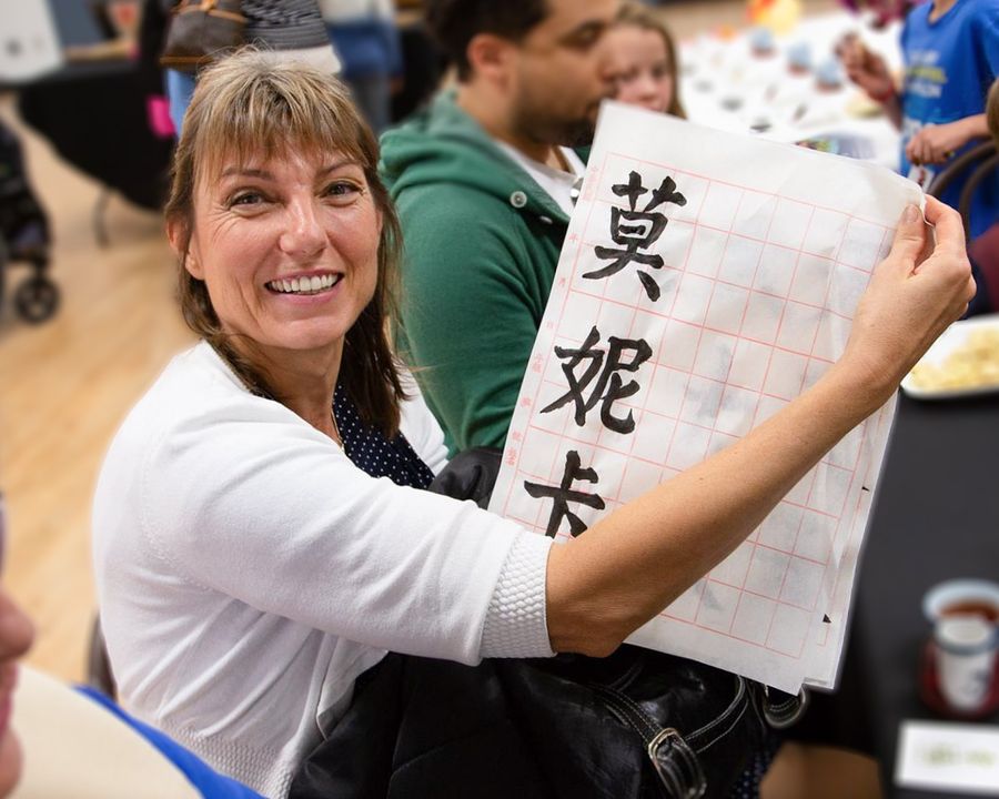 Community participant smiling while holding her Chinese calligraphy practice